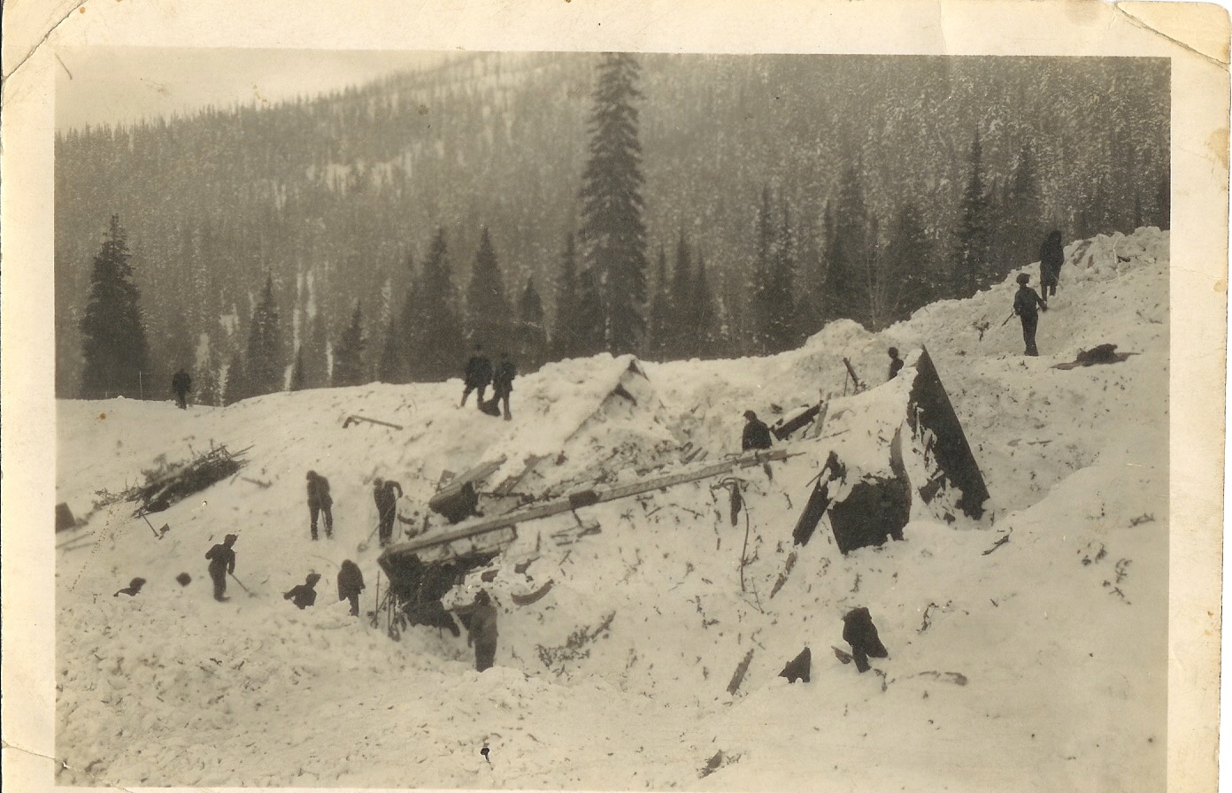 A sepia toned photo from 1910 shows people searching for survivors after a snowslide in Revelstoke