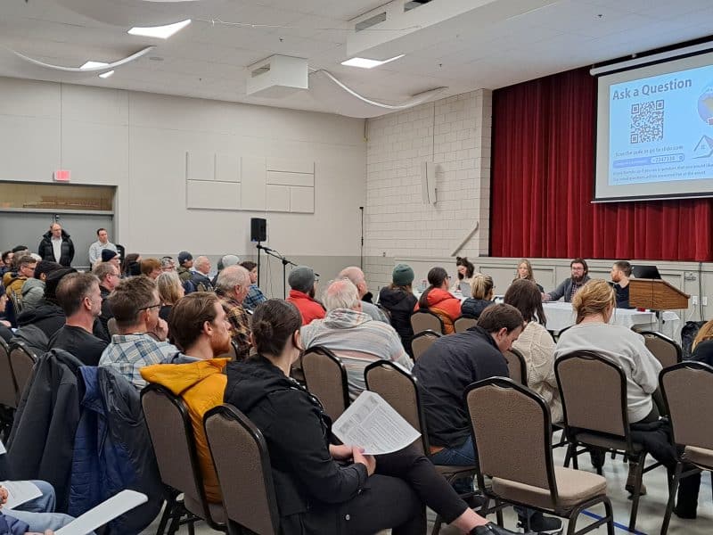 Revelstoke residents sitting in a gym watching a presentation for STR regulations in the city and the province.