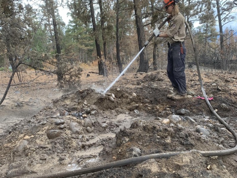 Wildland firefighter Joshua Day in the field with a hose working on a fire line.