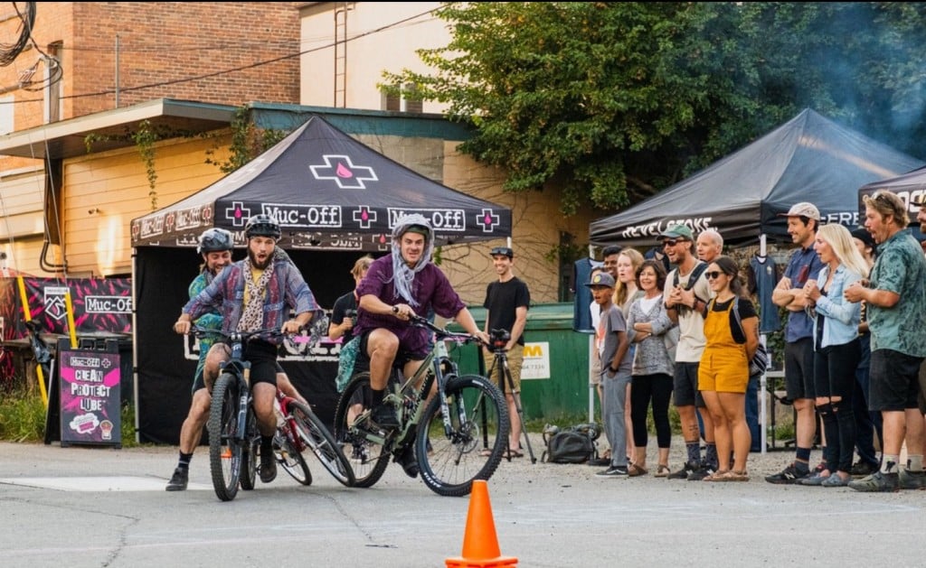 Two riders on street bikes try to knock each other out as race for a finish line.