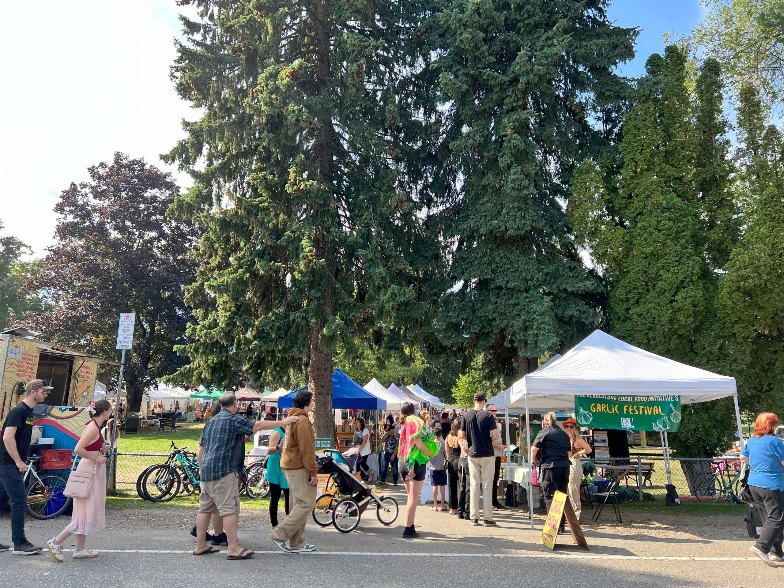 Vendors line a path with walkers and bike riders going past them.