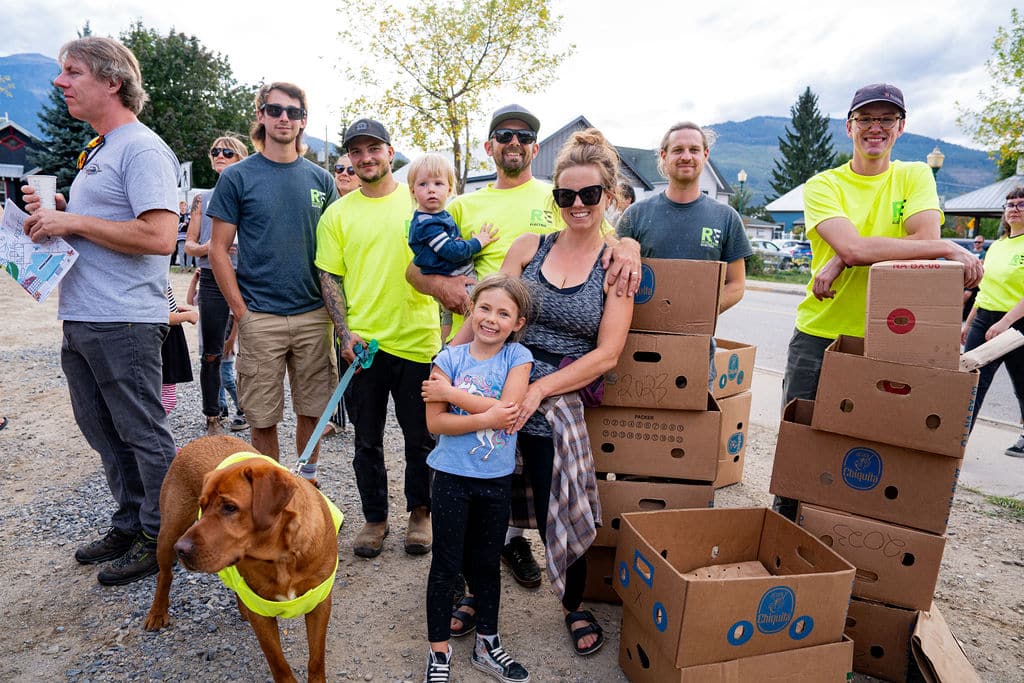 A collection of volunteers standing around boxes filled with food donations under a large white tent.