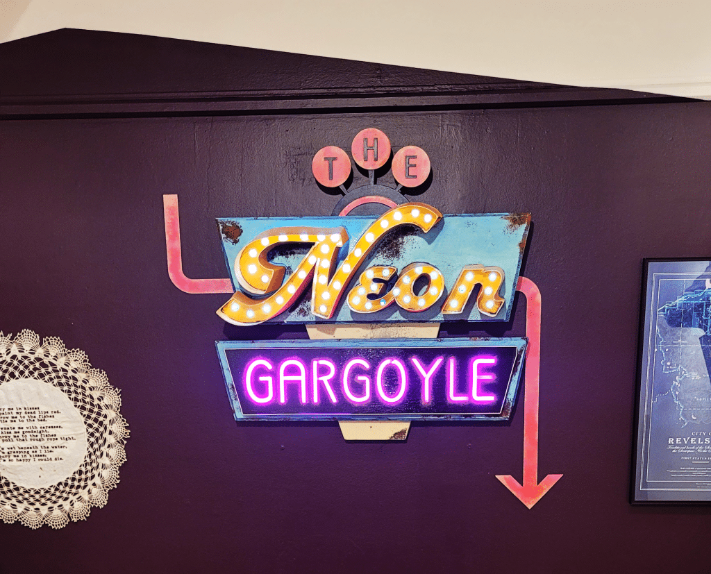 1950's style signage with neon lighting and three styles of test. The sign reads The Neon Gargoyle.